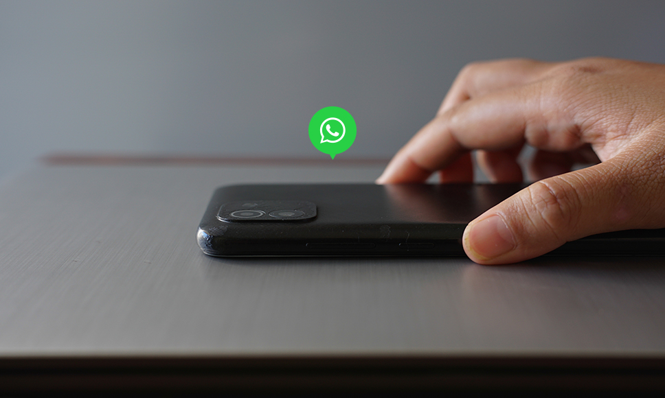 Mano acercándose a un móvil con el icono de WhatsApp flotando, sobre el ataque zero-click que hackea la app.